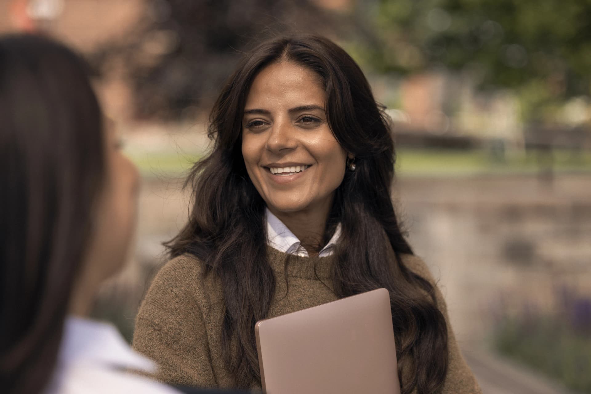 Portrait of a smiling woman holding documents outdoors.