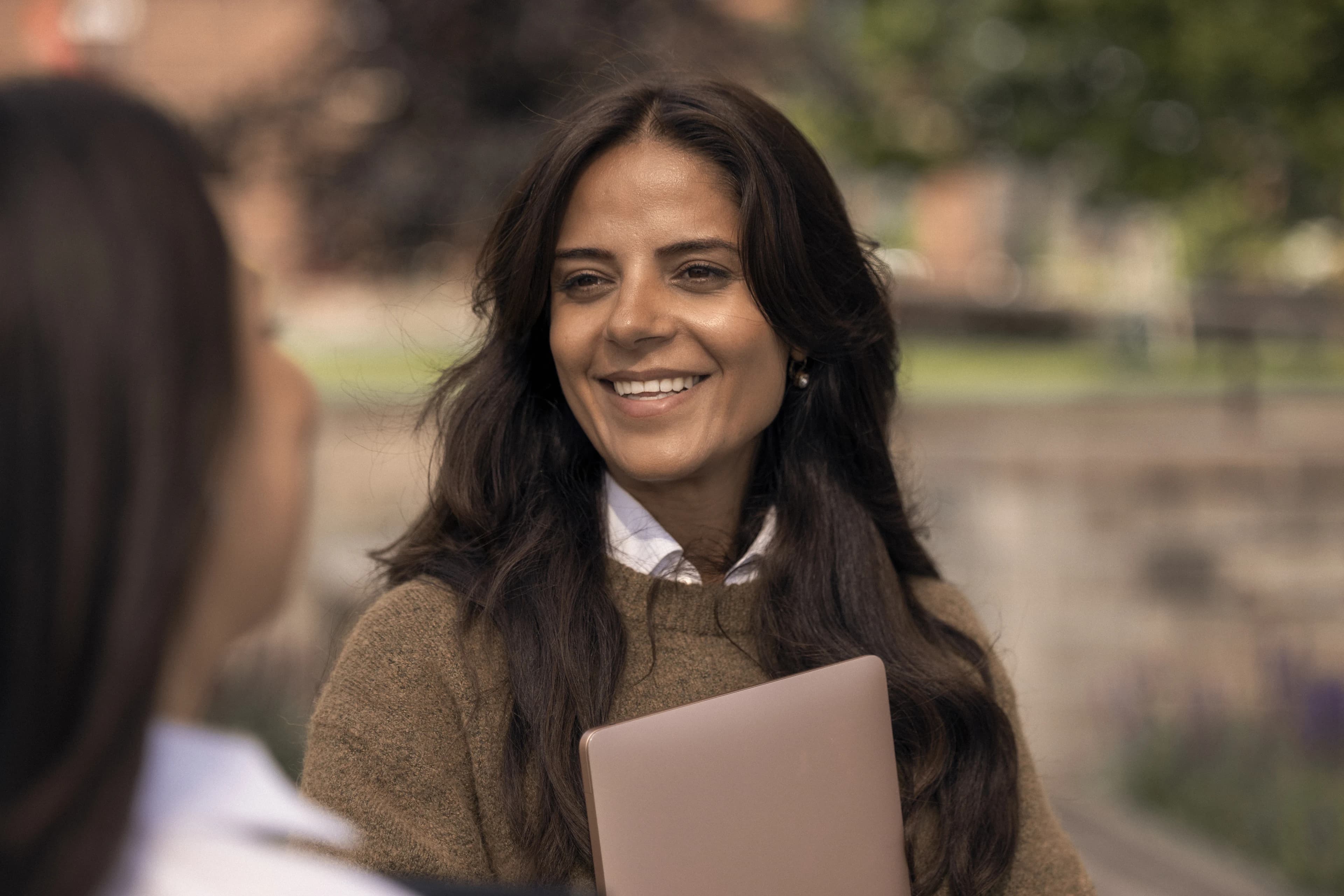 Portrait of a smiling woman holding documents outdoors.